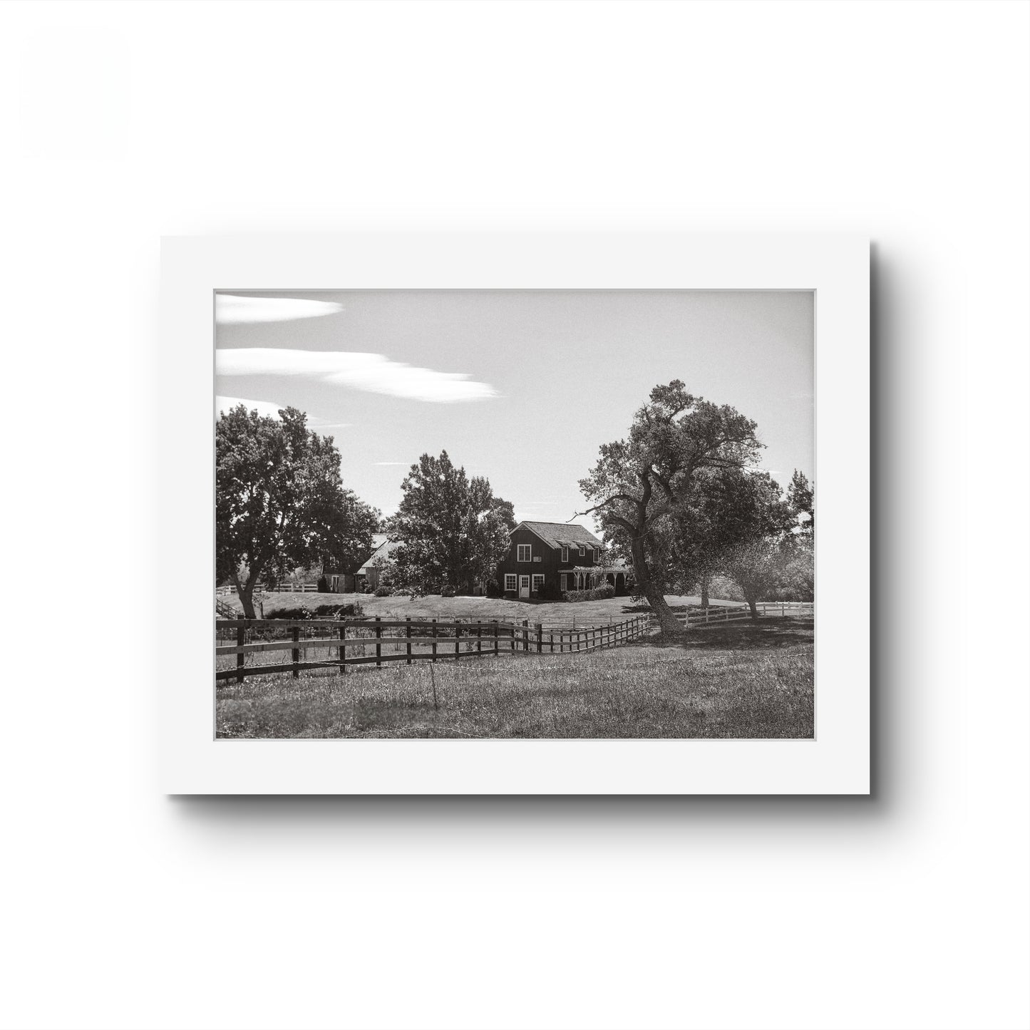 Matted black and white photo of a house on a prairie